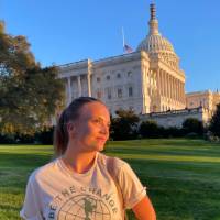 Female student standing outside of the united states capital and looking into the distance